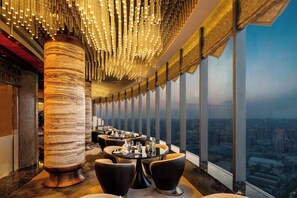 A high-rise restaurant with a panoramic city view, modern decor, and a unique ceiling light fixture. - Crowne Plaza Xian by IHG (Xi'an)