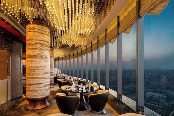 A high-rise restaurant with a panoramic city view, modern decor, and a unique ceiling light fixture. - Crowne Plaza Xian by IHG (Xi'an)