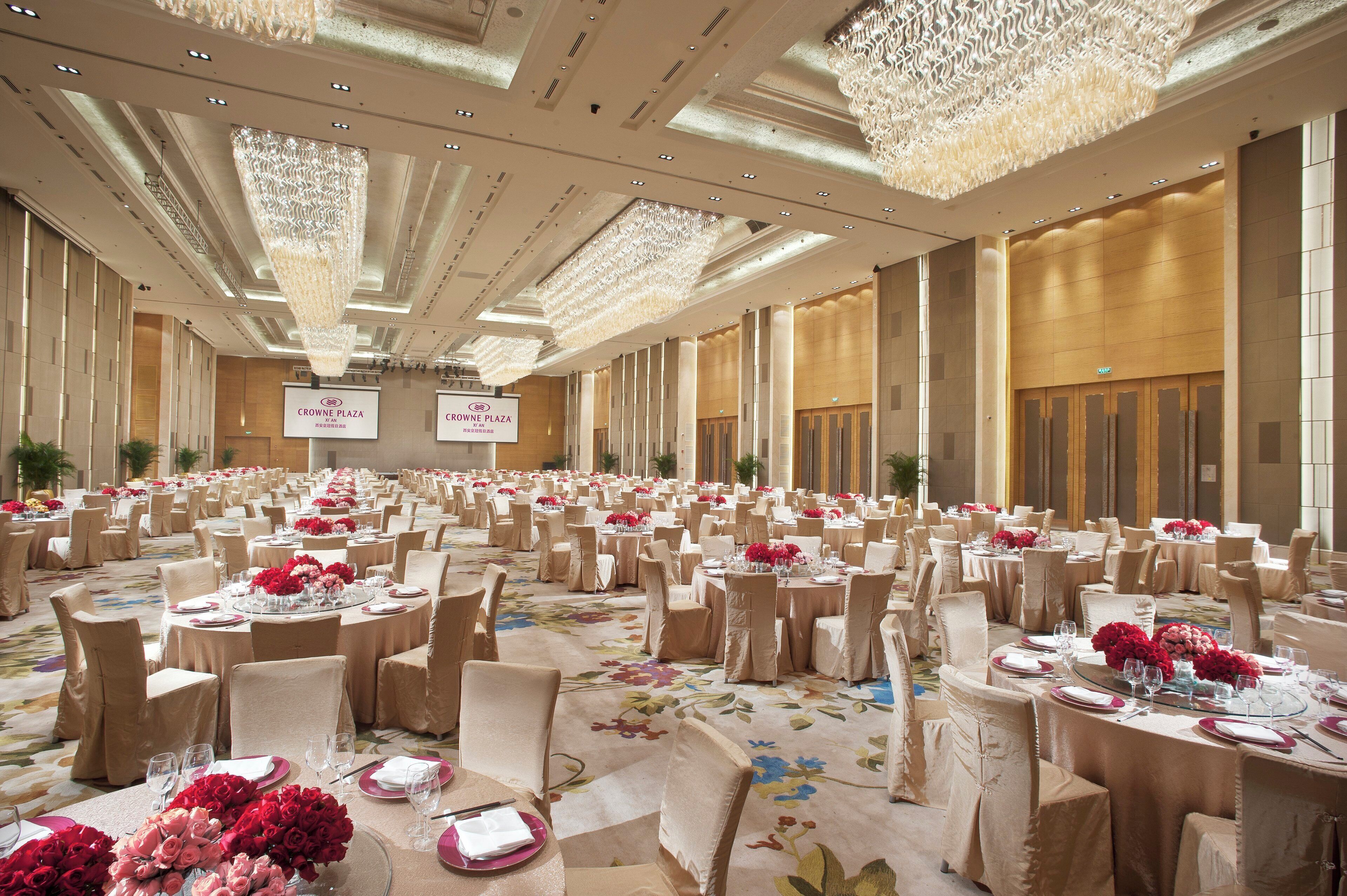 A banquet hall with round tables, chairs, and floral centerpieces.