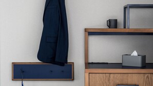 Un armario de madera con un cajón, un cuadro enmarcado colgado en la pared y un perchero con una chaqueta.