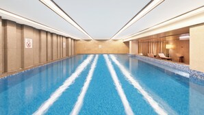 A large indoor swimming pool with clear water, surrounded by walls with a tiled pattern and a few lounge chairs. - Holiday Inn Chengdu Oriental Plaza by IHG (Chengdu)