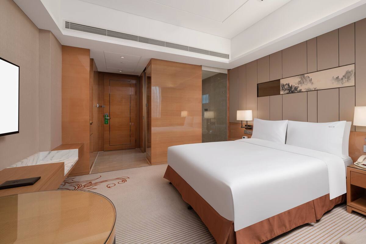 A hotel room with a large bed, bedside tables, a desk, and a chair.
