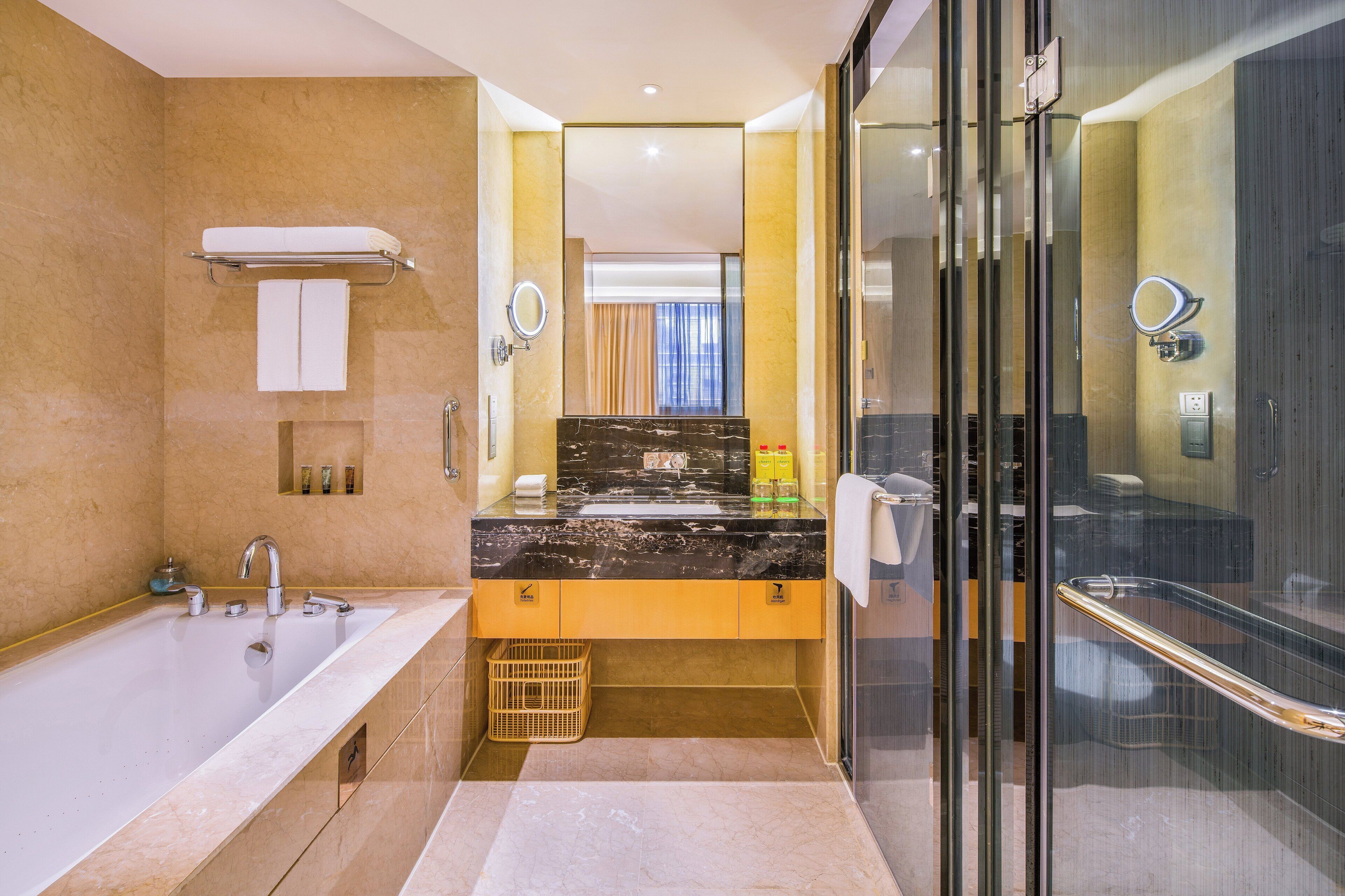 Un baño moderno con una bañera grande, un tocador con encimera de mármol negro y una cabina de ducha de cristal.