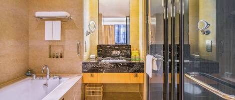 A modern bathroom with a large bathtub, a vanity with a black marble countertop, and a glass shower enclosure.
