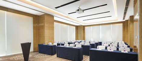 A conference room with rows of tables, chairs, and a podium.