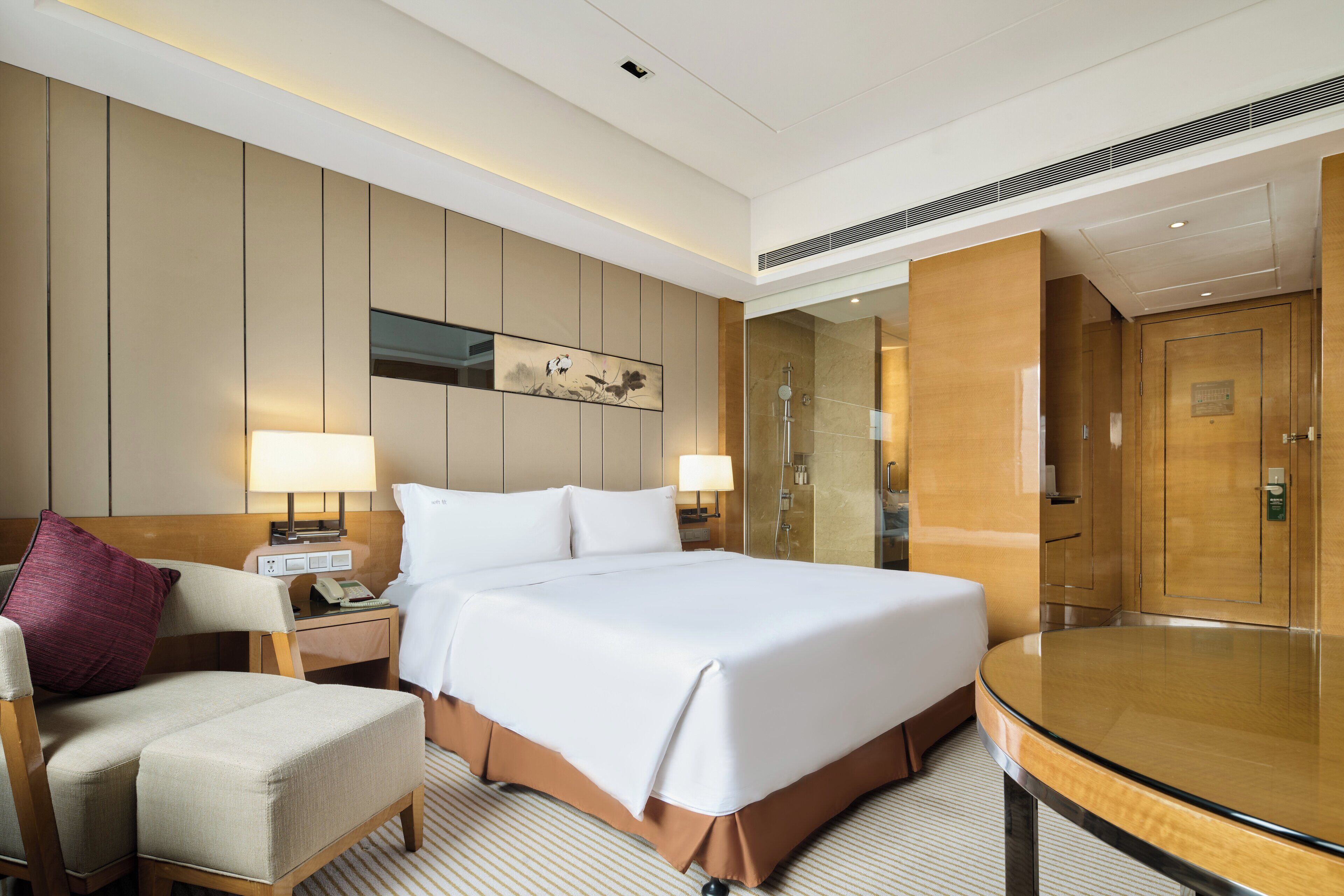 Quarto de hotel com uma cama, mesas de cabeceira, uma cadeira, um espelho e uma porta.