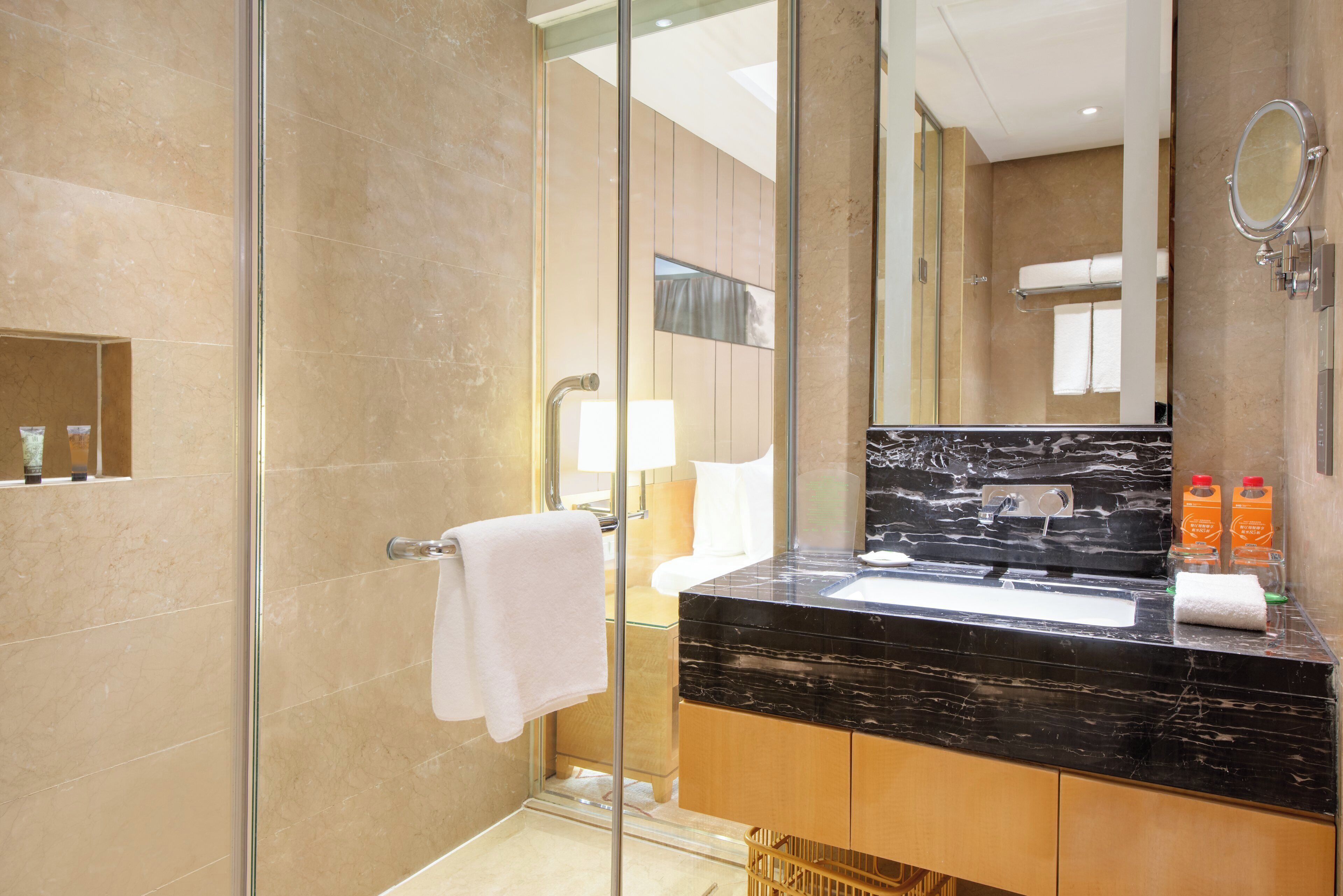 A modern bathroom with a glass shower enclosure, a marble sink, and a large mirror.