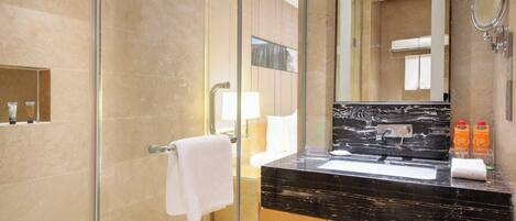 A modern bathroom with a glass shower enclosure, a marble sink, and a large mirror.
