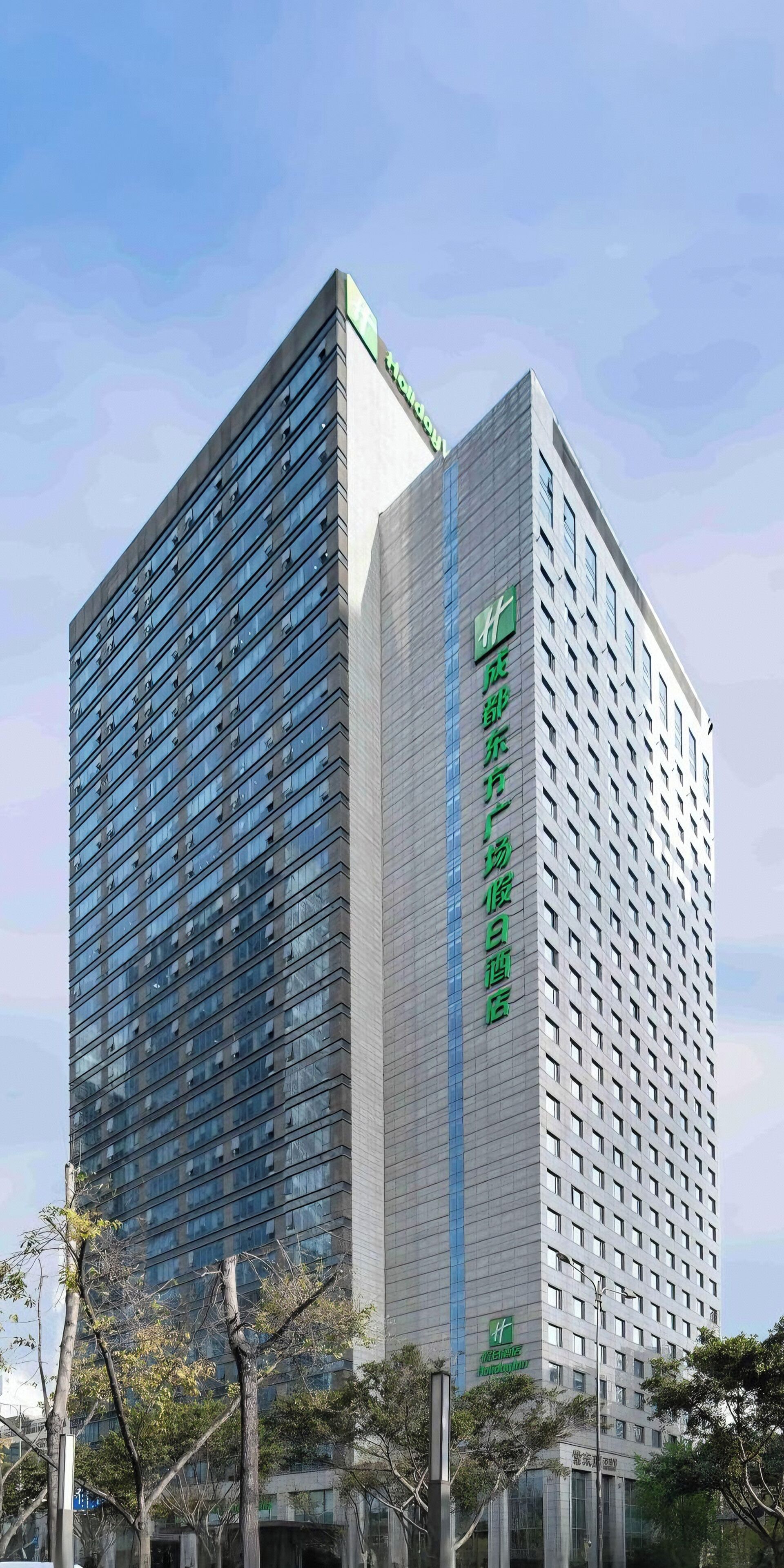 A modern hotel building with a prominent green logo and signage indicating it is a hotel.