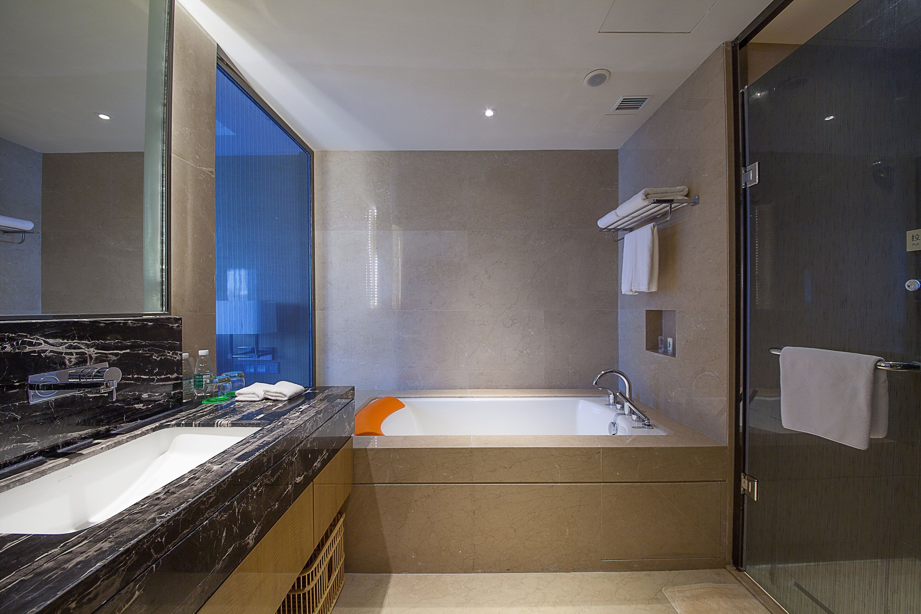 A modern bathroom with a marble sink, a bathtub, and a glass shower enclosure.