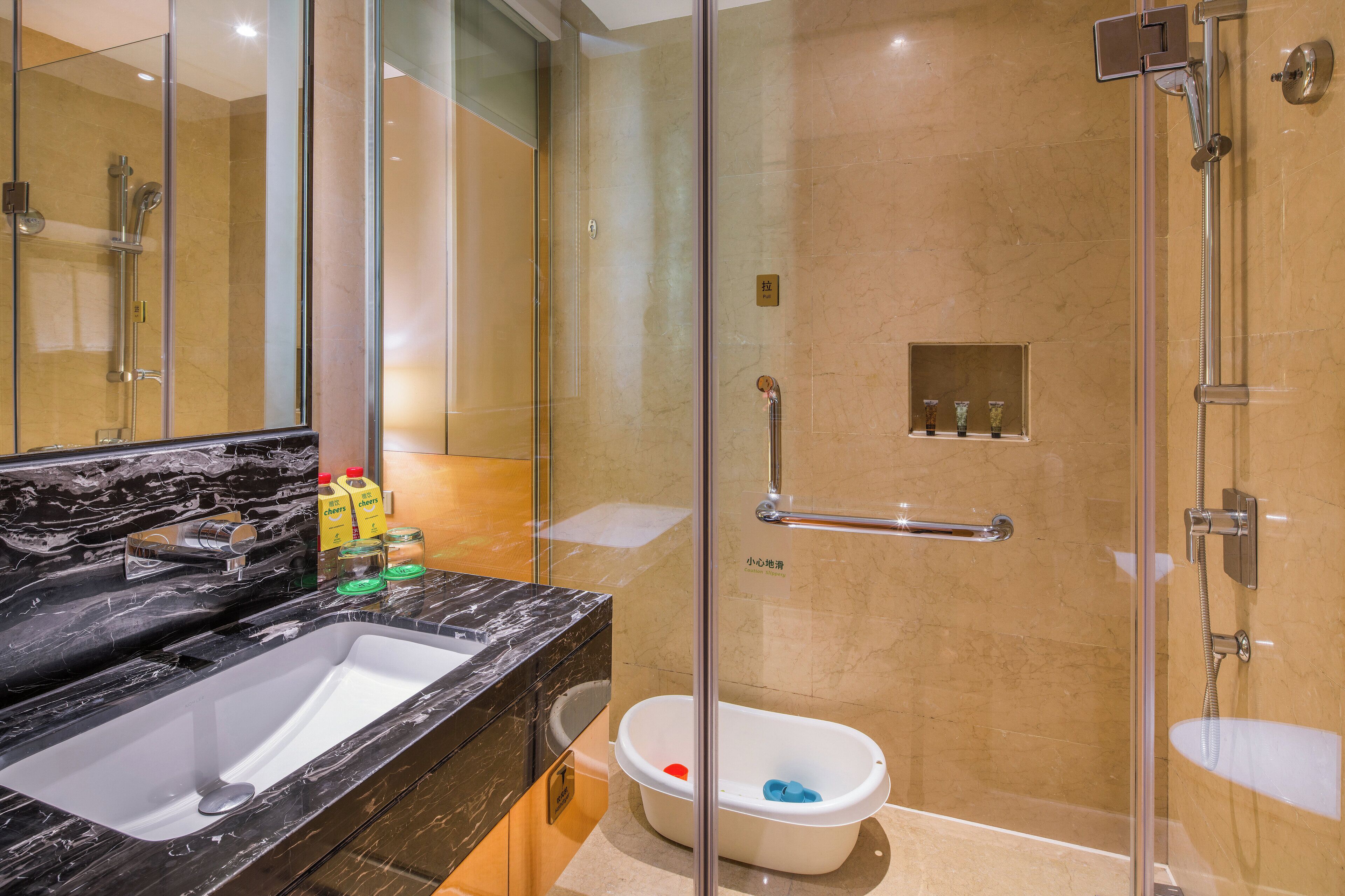 Une salle de bain moderne avec un grand lavabo, une douche à parois de verre et une petite étagère contenant des articles de toilette.