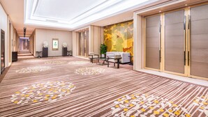 A hotel corridor with a patterned carpet, a reception desk, seating area, and a large sliding door. - Holiday Inn Chengdu Oriental Plaza by IHG (Chengdu)