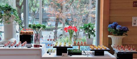 A buffet setup with various food items and decorative plants.