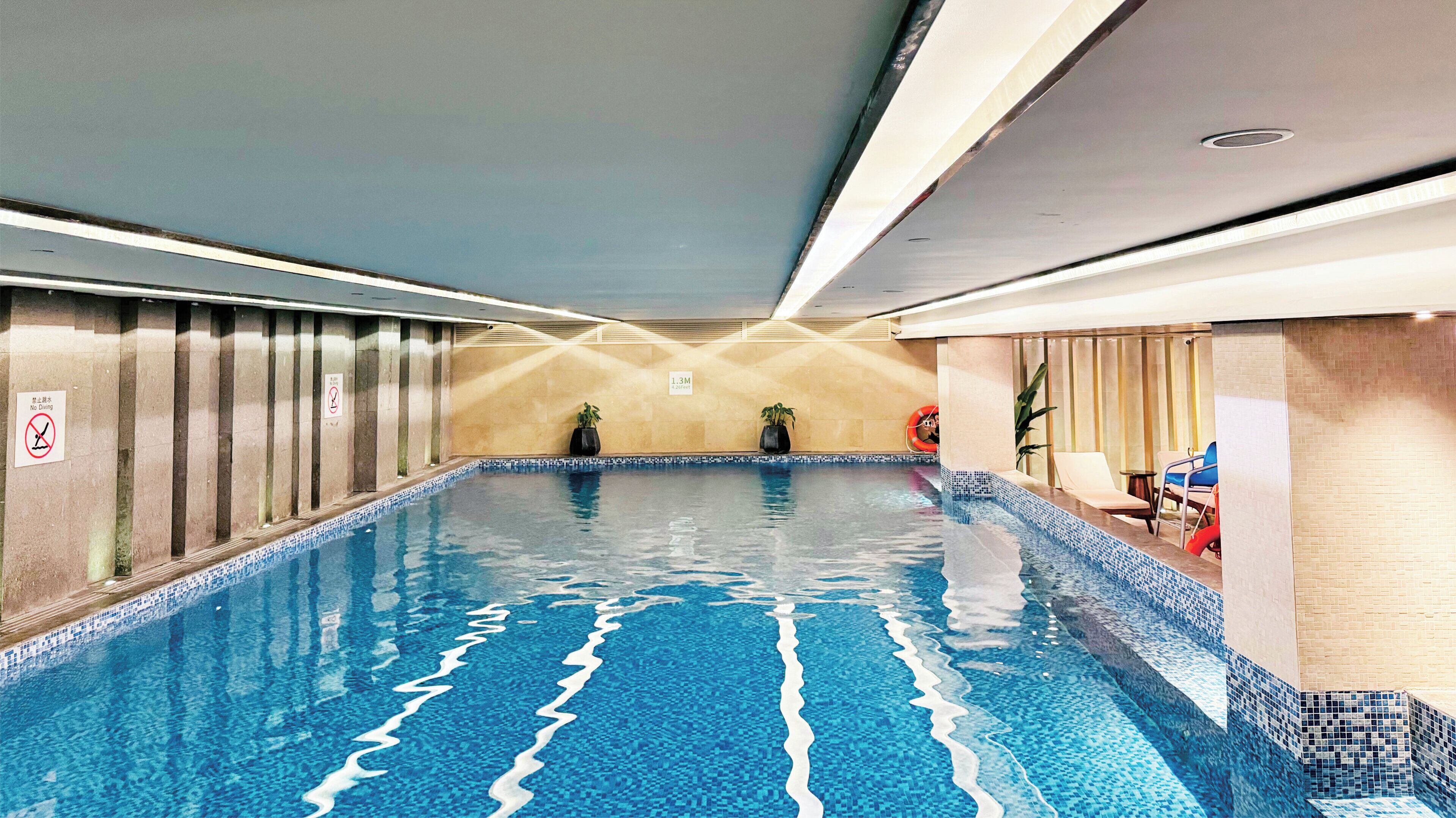 An indoor swimming pool with tiled walls and a no diving sign.