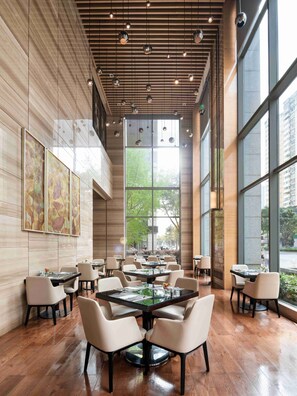 A modern dining area with wooden paneling, large windows, and contemporary lighting fixtures.
