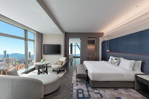 A modern hotel room with a large bed, a seating area with a round table, and a city view. - voco Suites Shenzhen Huanggang by IHG (Shenzhen)
