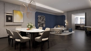 Un intérieur moderne avec une table de salle à manger ronde, des chaises, un canapé et un grand tableau abstrait accroché au mur.