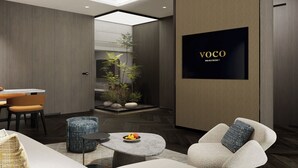Un interior moderno con comedor, asientos, un pequeño jardín y una pantalla de televisión mostrando 'VOCO'.