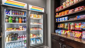 Un distributeur automatique rempli de boissons et d’en-cas, une étagère avec des produits emballés et un comptoir proposant d’autres en-cas.