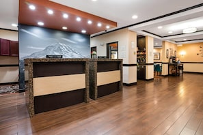 Un área de recepción con un mostrador de madera, un televisor montado en la pared y un cuadro enmarcado.