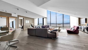 Un salon moderne doté d’un grand canapé, d’un coin repas et offrant une vue sur la mer.
