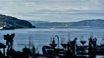 A view of a body of water with a distant ship, surrounded by hills and a small settlement.