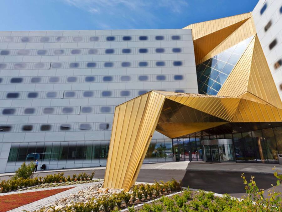 Un edificio moderno con un llamativo dosel geométrico en la entrada y fachada de vidrio reflectante.