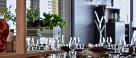 Interior moderno de restaurante con mesas y sillas de madera, cristalería y una escultura decorativa de un pájaro.
