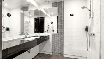 A modern bathroom with a large mirror, dual sinks, a shower area, and a tiled floor.