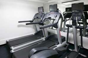 A gym with treadmills and elliptical machines, equipped with digital displays and speakers. - Club Quarters Hotel Covent Garden Holborn, London (London)