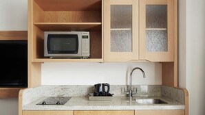 A kitchen with a microwave, a coffee maker, and a sink.