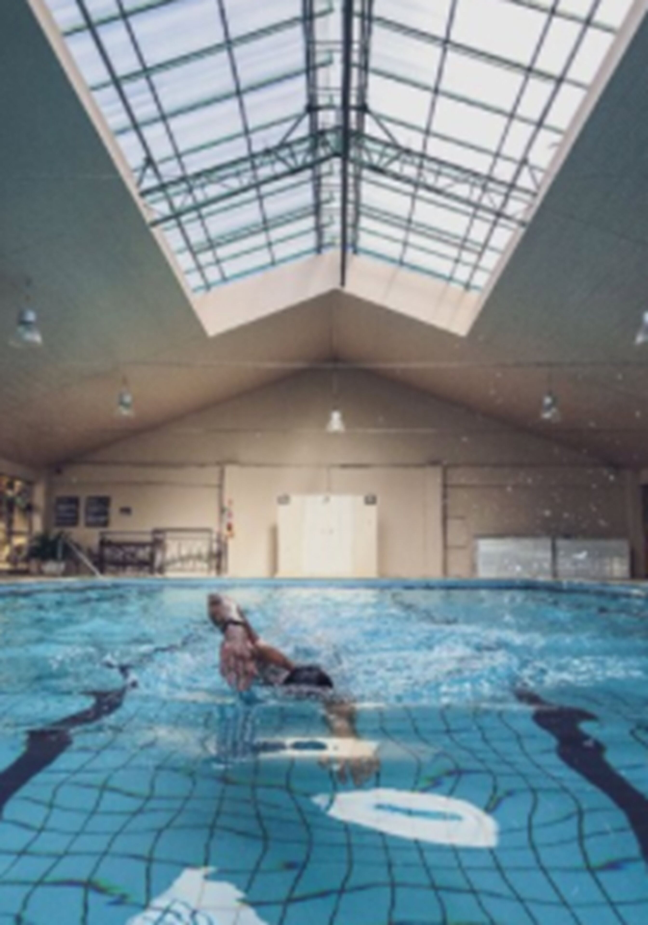 Piscina interna com teto alto e claraboia.
