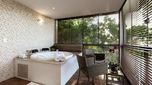A modern bathroom with a large bathtub, a wicker chair, and a small table with a potted plant. - Infinity Blue Resort & Spa (Balneário Camboriú)