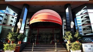 The entrance of Sun & Sands Downtown Hotel with a large red awning, glass doors, and potted plants. - Sun And Sands Downtown (Dubai)
