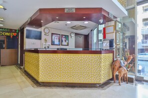 A reception area with a reception desk, a clock, framed pictures, and a glass partition. - Sun And Sands Downtown (Dubai)