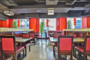 A restaurant interior with booths and tables, red and white decor, and a view of the street outside. - Sun And Sands Downtown (Dubai)