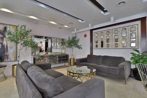 A modern living room with grey sofas, a glass coffee table, and a decorative mirror wall. - Sun And Sands Downtown (Dubai)