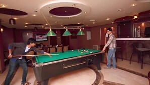 A pool table in a room with a bar area, chairs, and a television. - Sun And Sands Downtown (Dubai)