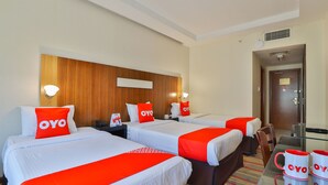 A hotel room with three beds, each with a red and white bedspread and pillows, and a small table with two mugs. - Sun And Sands Downtown (Dubai)