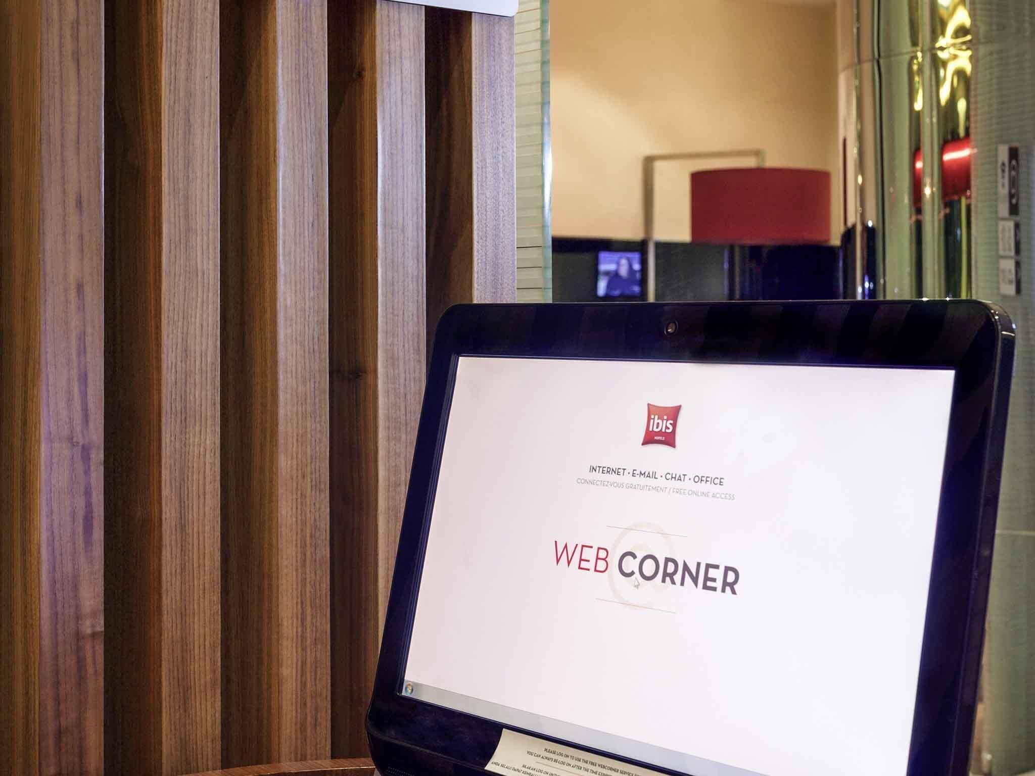 Una tableta mostrando una página web titulada 'WEB CORNER' con información sobre internet, correo electrónico, chat y servicios de oficina.