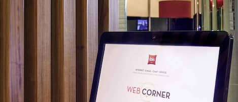 Una tableta mostrando una página web titulada 'WEB CORNER' con información sobre internet, correo electrónico, chat y servicios de oficina.