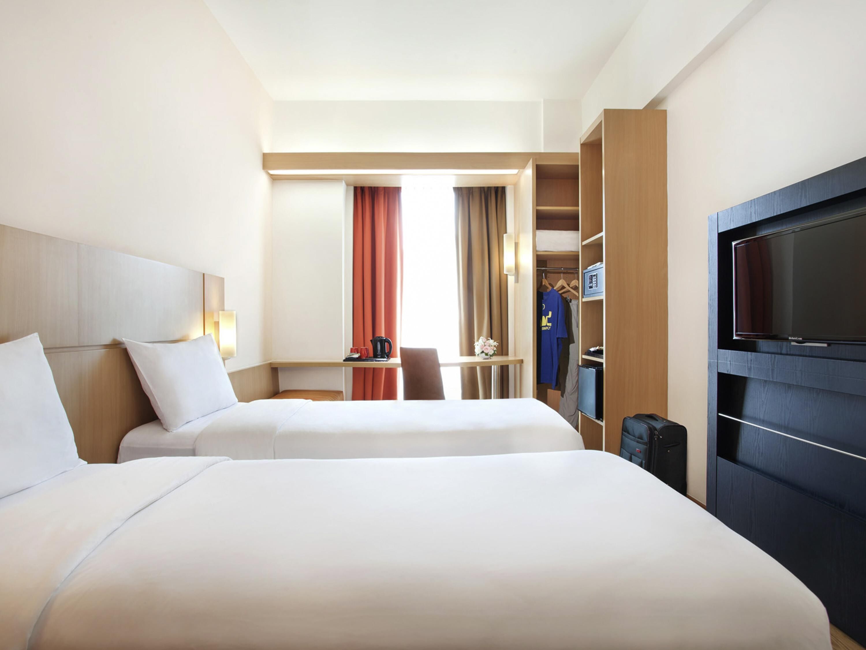 Ett hotellrum med två sängar, ett skrivbord, en TV och en garderob.
