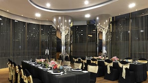 A conference room with round tables, black chairs, and gold sashes.