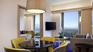 A modern hotel room with a dining area, a sofa, and a TV.