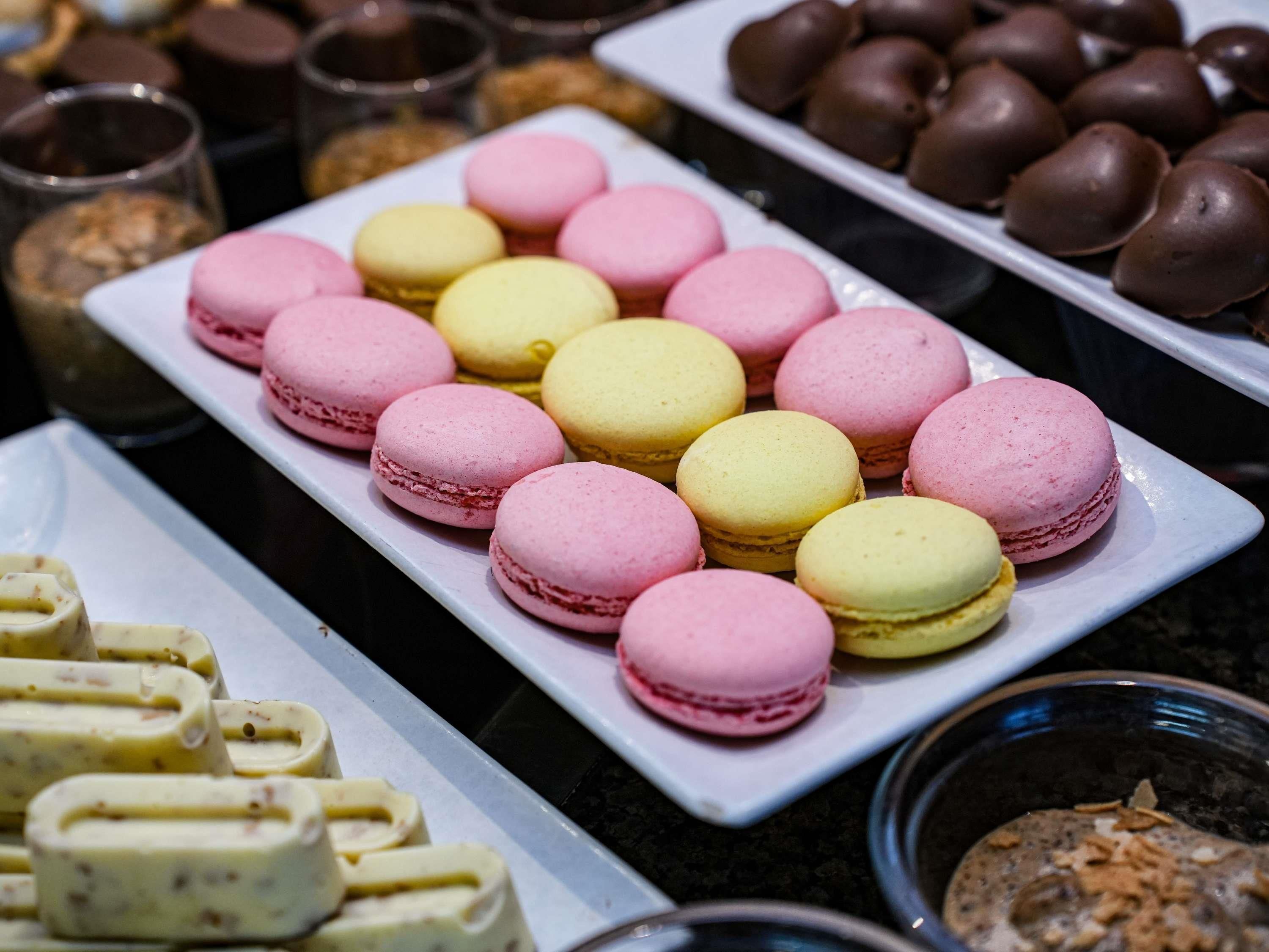 Una variedad de postres, incluyendo macarons rosa y amarillos, bombones cubiertos de chocolate y otras delicias horneadas.