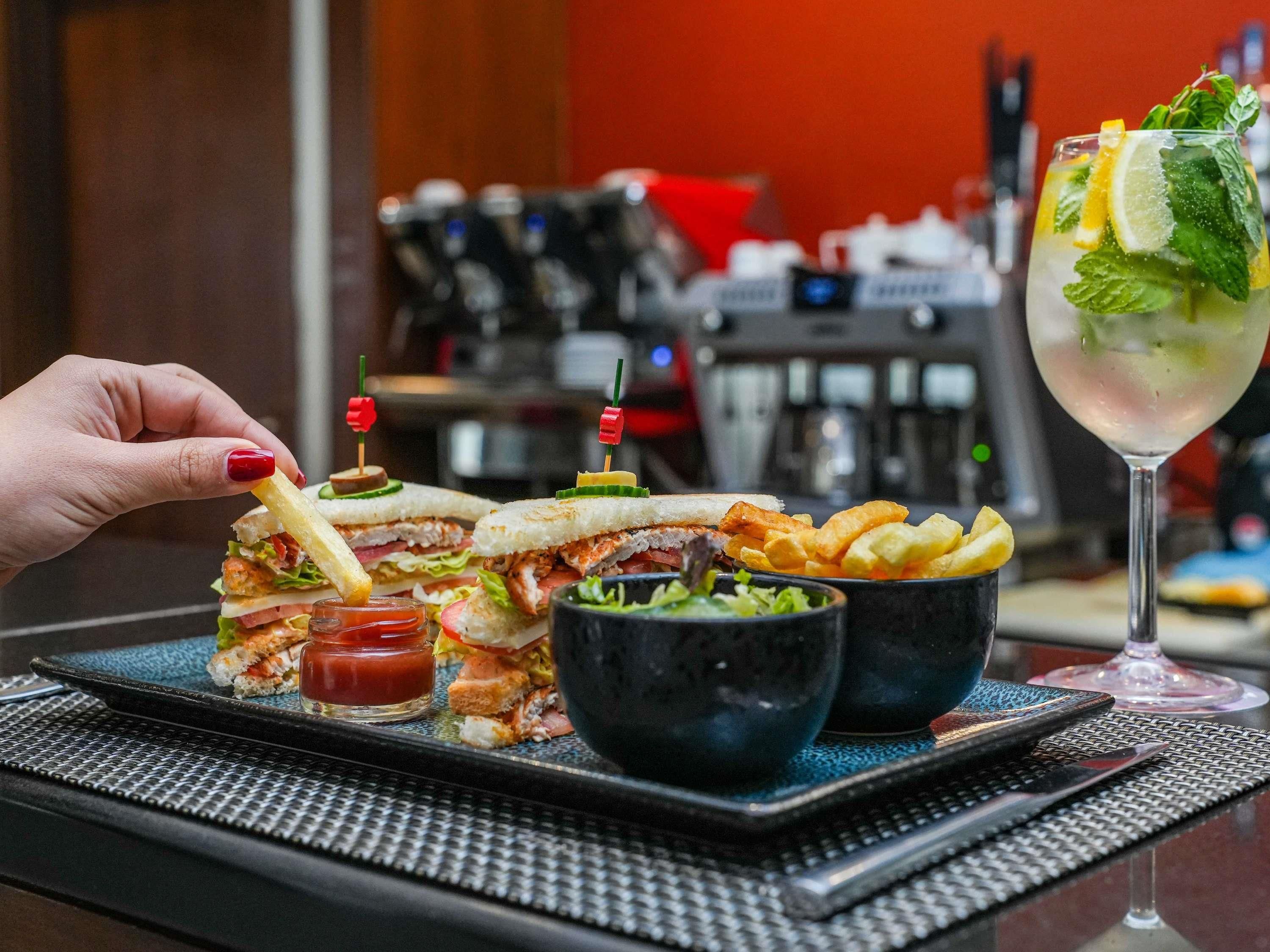 A tray with a sandwich, fries, and a drink on a table.