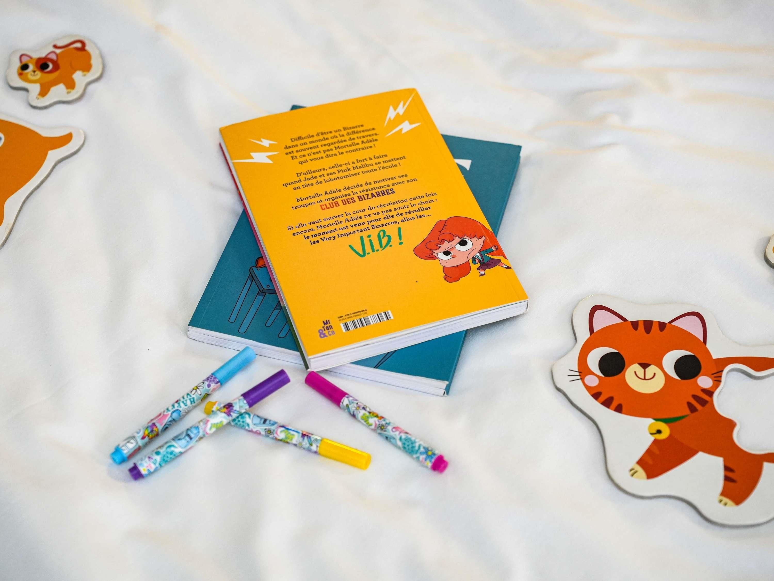 A book titled 'V.I.B.' with a cartoon character on the cover, placed on a white surface with colorful markers and a tiger-shaped cutout.
