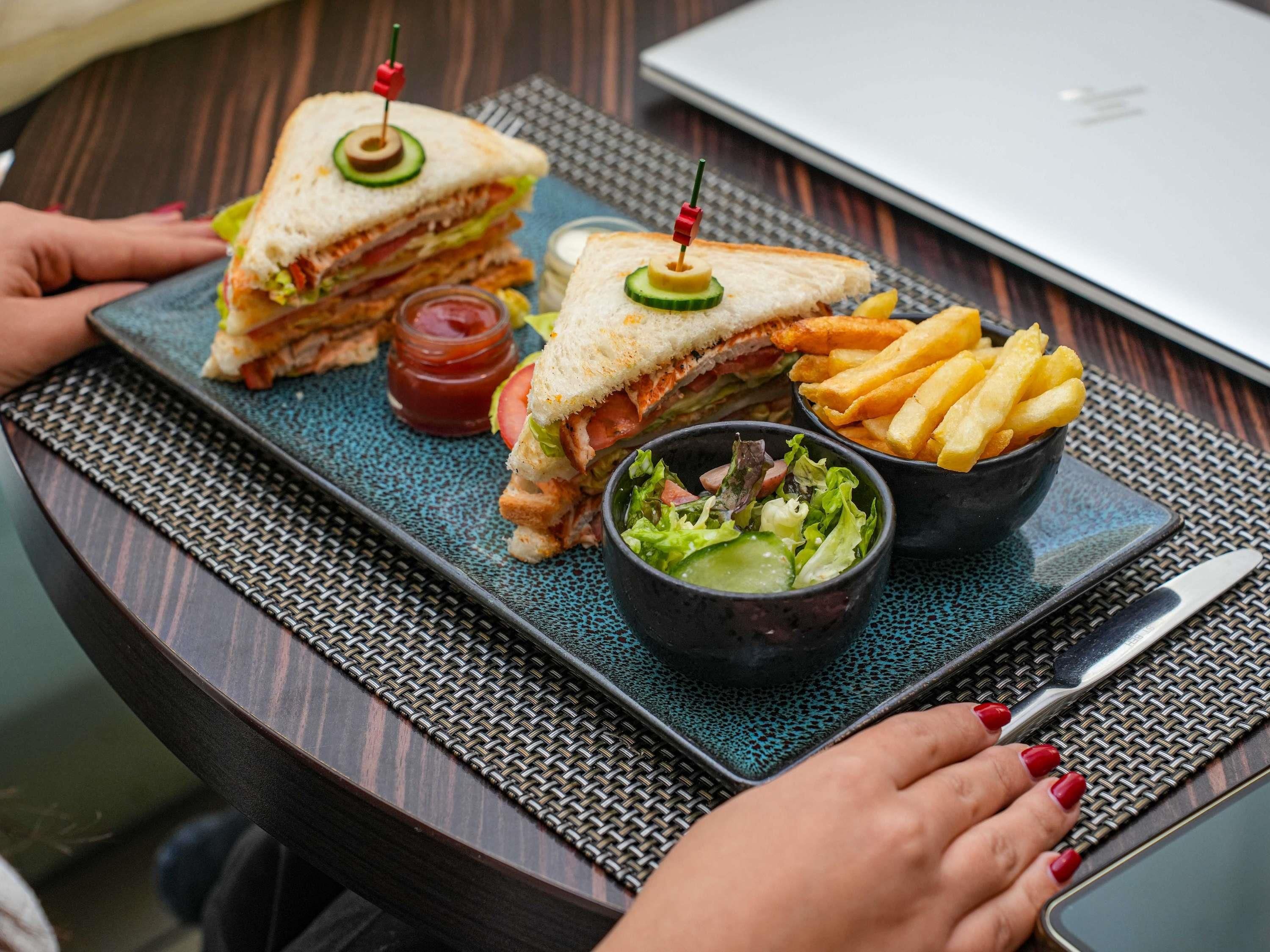 Una comida que incluye un sándwich, papas fritas y una ensalada, sobre una bandeja.