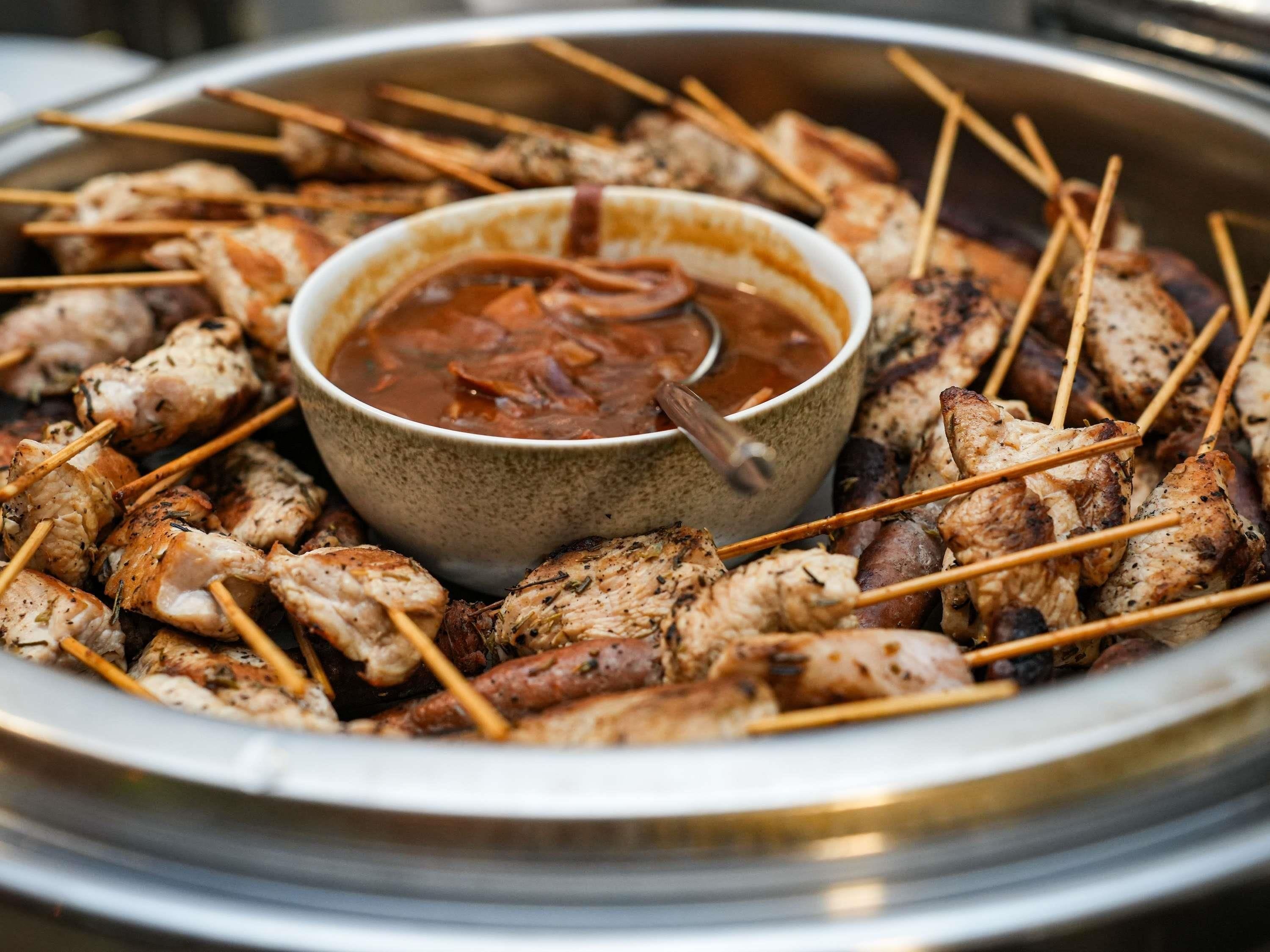 A platter of skewered meats with a dipping sauce in the center.