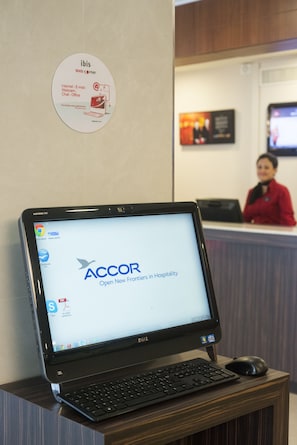 Un ordinateur portable sur un bureau, avec une pancarte au-dessus, et un espace d’accueil en arrière-plan.